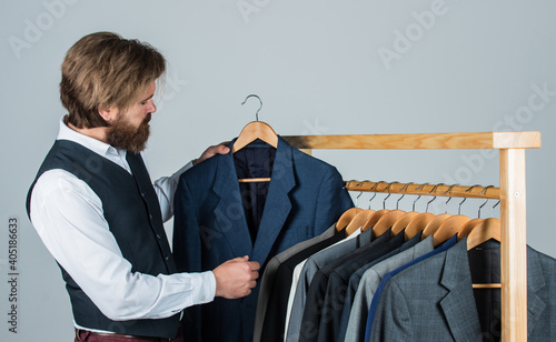 Obraz na plátne Bearded man customer looking for his size formal suit, exclusive garments concep