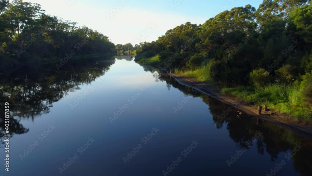 Forward flight low over river with mirror-like water surface and tree reflections at sunset Forward flight low over river with mirror-like water surface and tree reflections at sunset