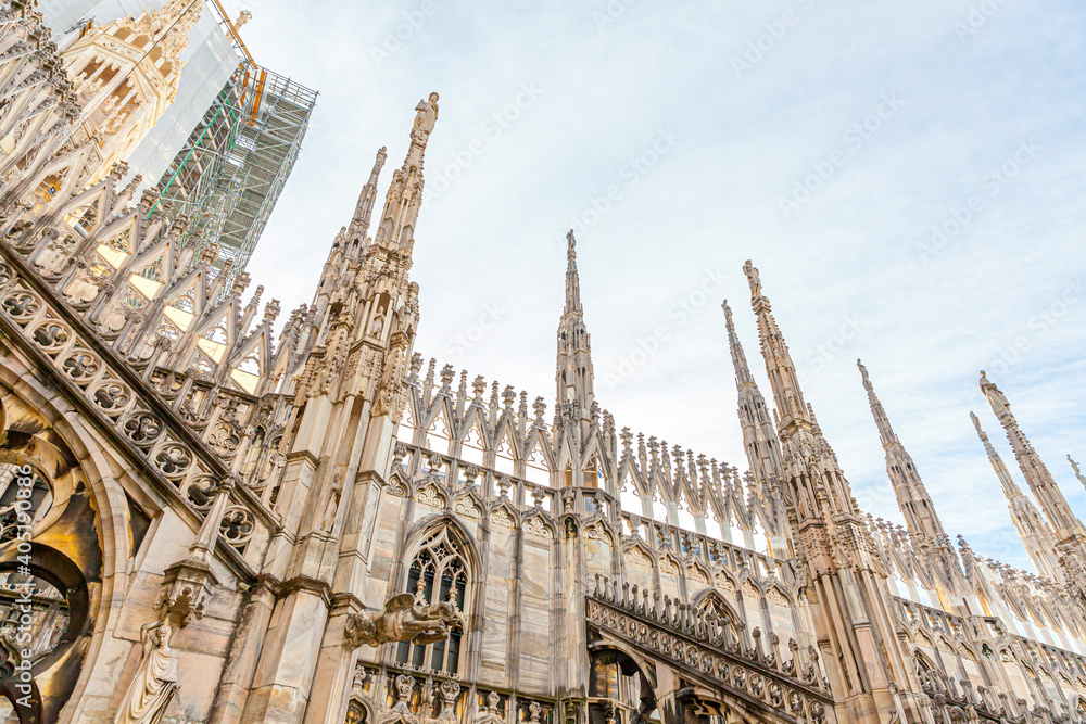 Roof of Milan Cathedral Duomo di Milano with Gothic spires and white marble statues. Top tourist attraction on piazza in Milan, Lombardia, Italy. Wide angle view of old Gothic architecture and art. Roof of Milan Cathedral Duomo di Milano with Gothic spires and white marble statues. Top tourist attraction on piazza in Milan, Lombardia, Italy. Wide angle view of old Gothic architecture and art.