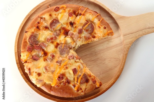 top view of pizza in wooden tray on white table