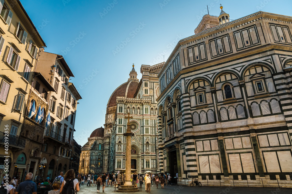View of Piazza del Duomo in Florence. The square contains the San Zanobi Column next to the Baptistery San Giovanni. Behind is the Santa Maria del Fiore Cathedral with Dome and Giotto's bell tower.