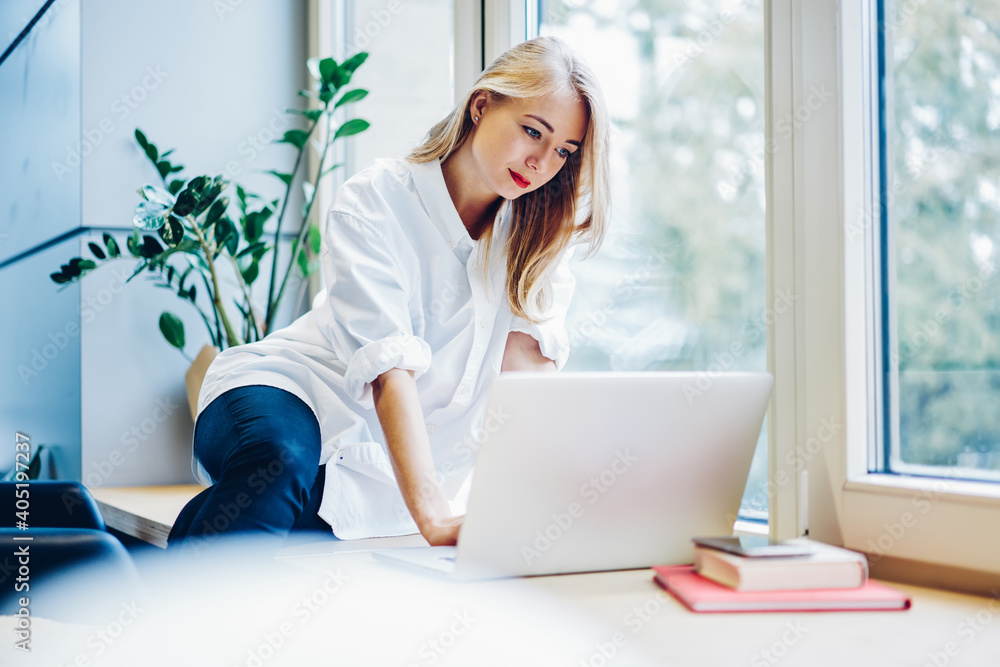 Young female using laptop near window Young female using laptop near window