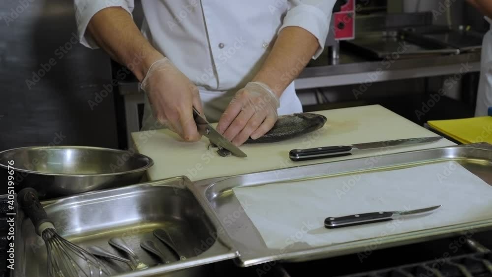Close-up of a gloved chef carving a Dorado fish on a chopping Board in the restaurant's kitchen. The process of cooking fish with lemon in the kitchen. Close-up of a gloved chef carving a Dorado fish on a chopping Board in the restaurant's kitchen. The process of cooking fish with lemon in the kitchen.
