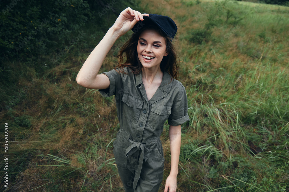 Woman in the forest cheerful woman in green jumpsuit black cap smile outdoor recreation
