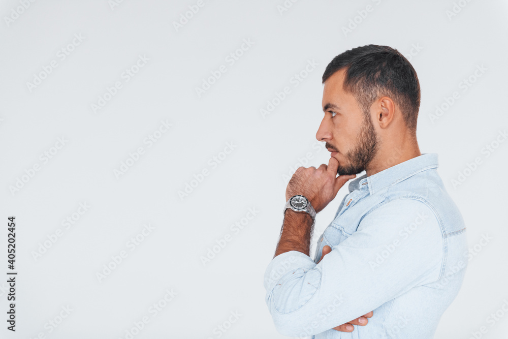 Side view. Young handsome man standing indoors against white background Side view. Young handsome man standing indoors against white background