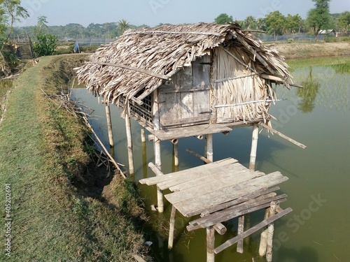 small hut made of bamboo and nipa palm leaves. It is used to watch over the  fish culture area of south asian country. photo