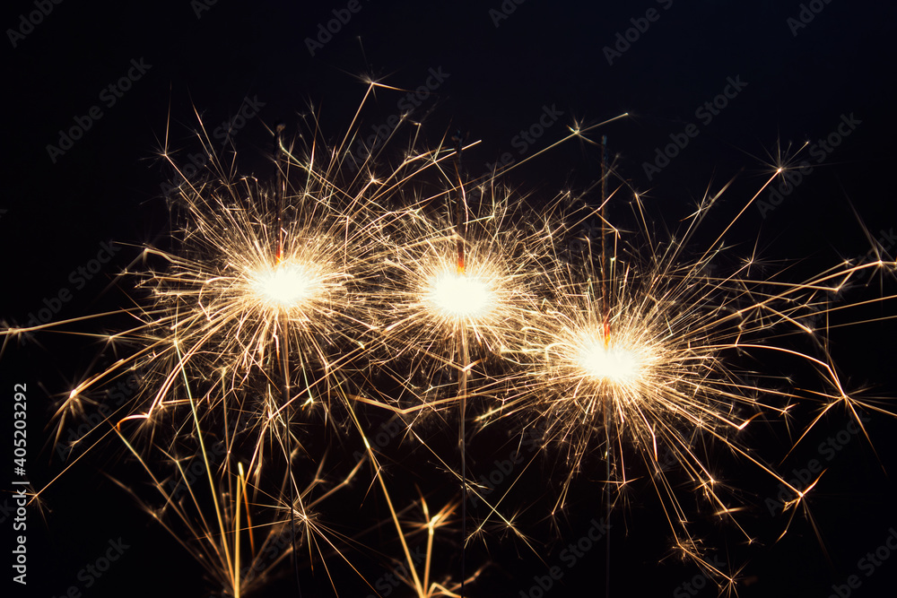 New year celebration greeting card with three burning sparklers with spiky flames on black background.