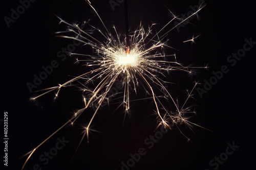 Close up of one burning pyrotechnic sparkler on black background. 
