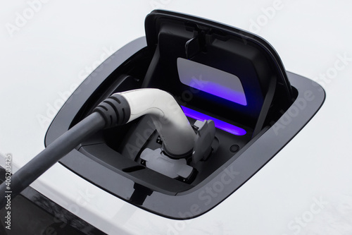 Closeup of a socket of charging electric car with plugged in charger from electric station.