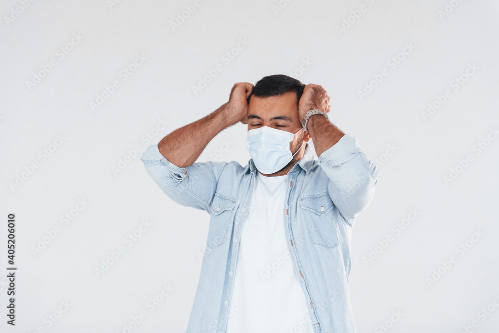 Headache and pain. Young handsome man standing indoors against white background Headache and pain. Young handsome man standing indoors against white background