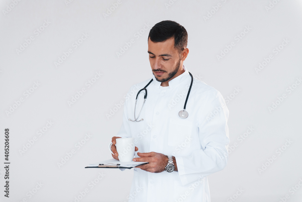 Medic in uniform. Young handsome man standing indoors against white background Medic in uniform. Young handsome man standing indoors against white background