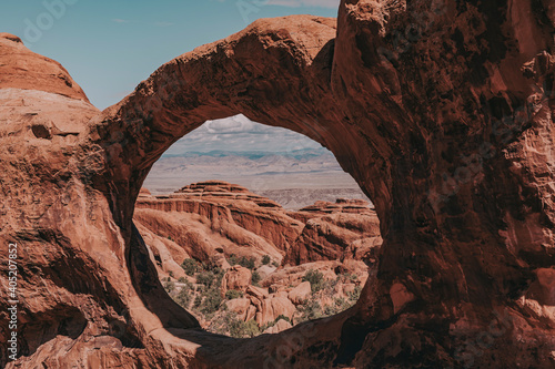 The top window of the Double O Arch frames sandstone rock formations in Arches National Park, Utah, USA. © Bella B Photography