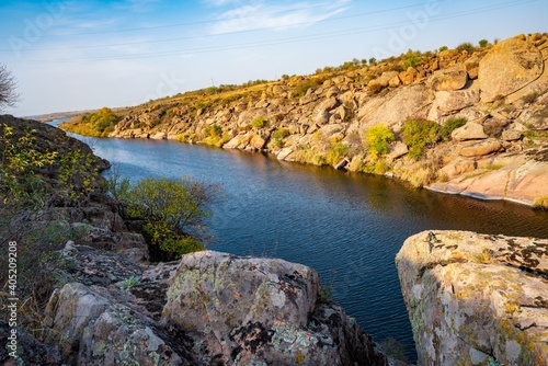 A large number of stone minerals covered with vegetation lying over a small river in picturesque Ukraine