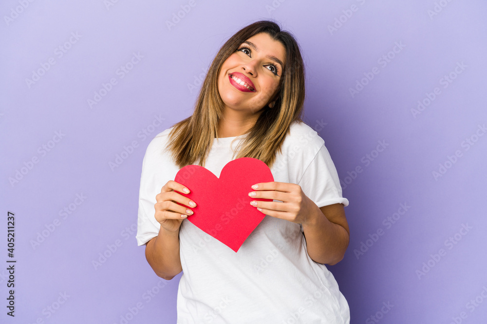Young indian woman holding a valentines day heart isolated dreaming of achieving goals and purposes Young indian woman holding a valentines day heart isolated dreaming of achieving goals and purposes