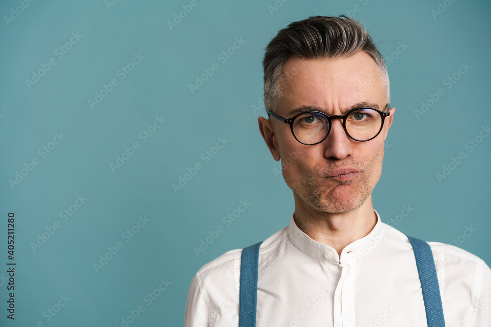 Displeased grey-haired man in eyeglasses grimacing and looking at camera Displeased grey-haired man in eyeglasses grimacing and looking at camera