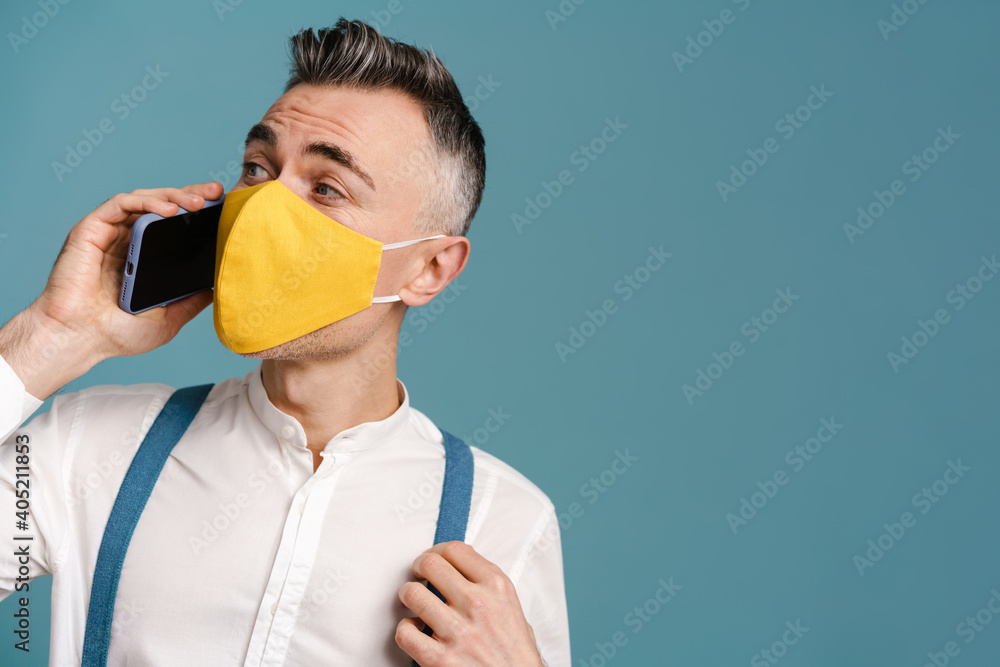 Pleased grey-haired man in face mask talking on mobile phone Pleased grey-haired man in face mask talking on mobile phone