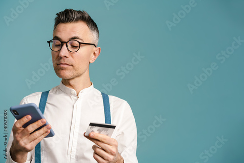 Serious grey-haired man posing with cellphone and credit card photo