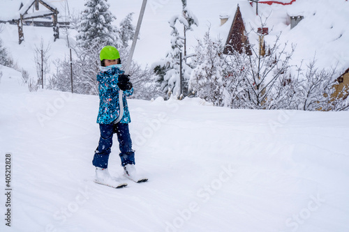 Blurred focus background. A girl lifting on the ski drag lift rope in blue sport outfit on the ski resort mountain do a ski lesson during a snowfall. Ski resort in french mountain. High quality photo