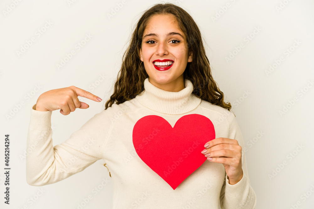 Young caucasian woman holding a heart valentines day shape isolated person pointing by hand to a shirt copy space, proud and confident Young caucasian woman holding a heart valentines day shape isolated person pointing by hand to a shirt copy space, proud and confident
