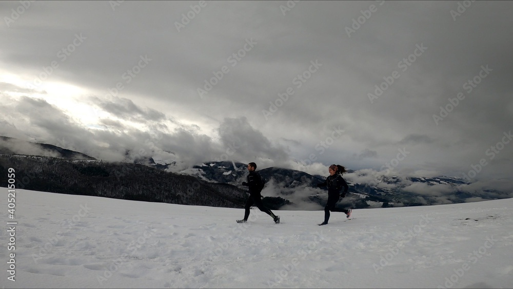 young couple running in a snowed mountain