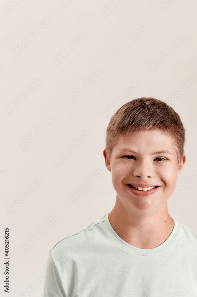 Close up portrait of cheerful disabled boy with Down syndrome smiling at camera while posing isolated over white background Close up portrait of cheerful disabled boy with Down syndrome smiling at camera while posing isolated over white background