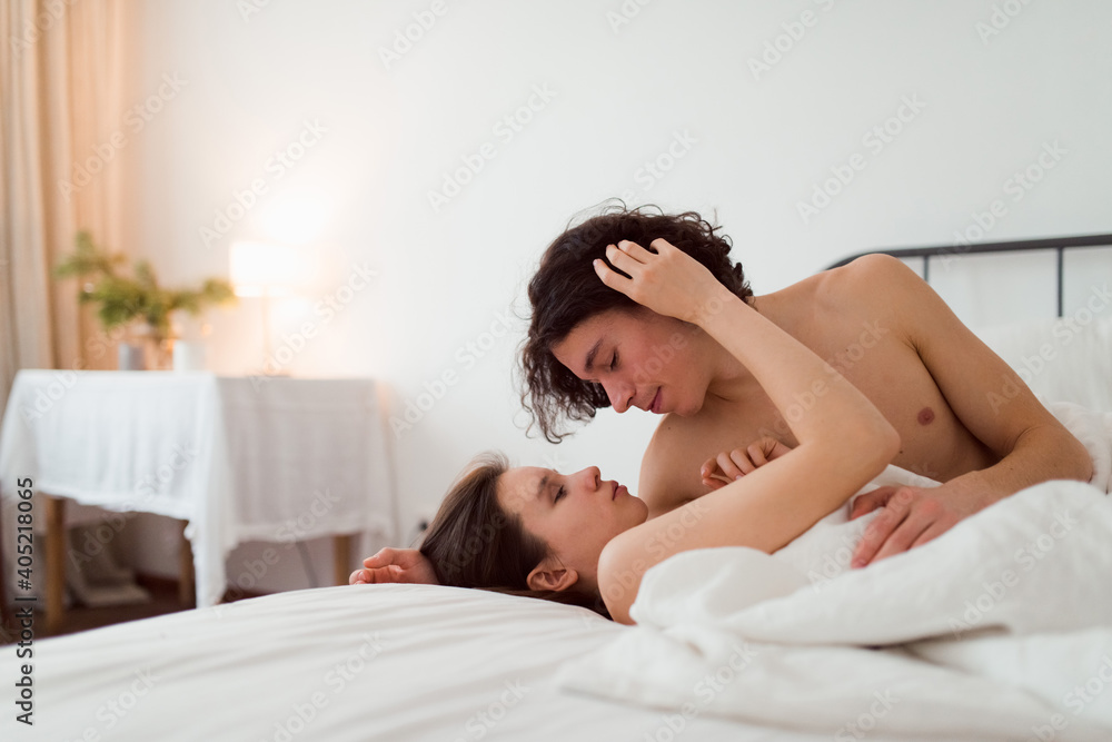 young loving couple embracing in bed, man and woman intimacy, lifestyle indoor portrait young loving couple embracing in bed, man and woman intimacy, lifestyle indoor portrait