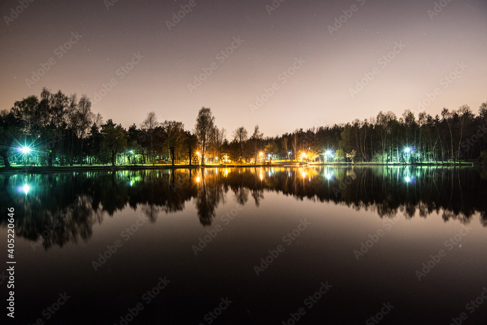 Obraz premium Night park, evening sky with stars. Park in city lake with refleNight park, evening sky with stars. Park in city lake with reflections on water. Sosnowiec, Polandctions in water. Sosnowiec, Poland