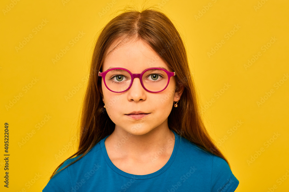 Little girl with eyeglasses isolated on yellow background. Vision correction for children