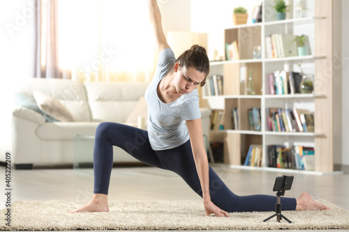 Woman learning yoga poses watching tutorial on phone © PheelingsMedia