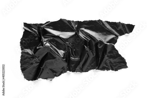 Torn and crumpled piece of black glossy magazine paper isolated on white background. Copy space for text.