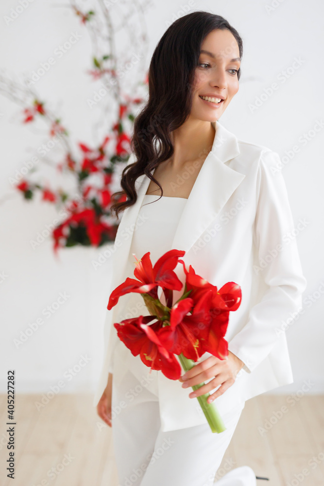 Fashionable bride in a white trouser suit. Ceremony arch of red poinsettia. Wedding in winter season. Fashionable bride in a white trouser suit. Ceremony arch of red poinsettia. Wedding in winter season.