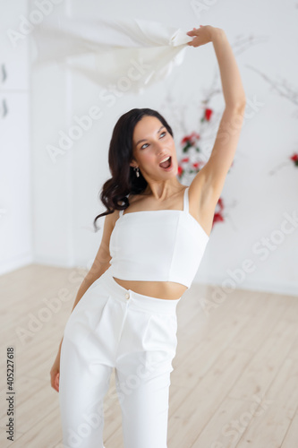Happy Fashionable bride in a white trouser suit. Ceremony arch of red poinsettia. Wedding in winter season.