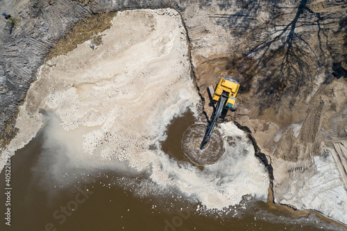 Yellow excavator digger working. Excavator digging sand, ground from water. Industrial aerial drone view. photo