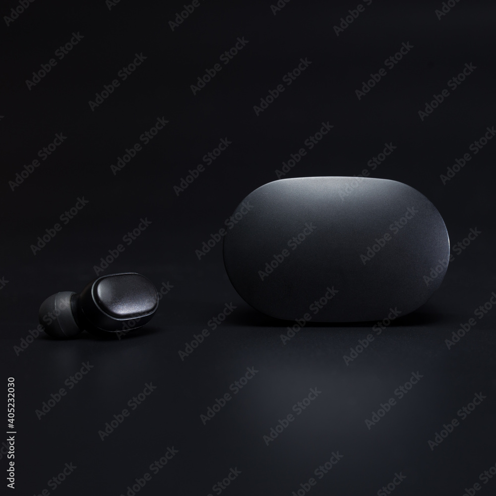 Wireless headphones close up. Black earphone close up with charging case. Wireless headphones close up. Black earphone close up with charging case.