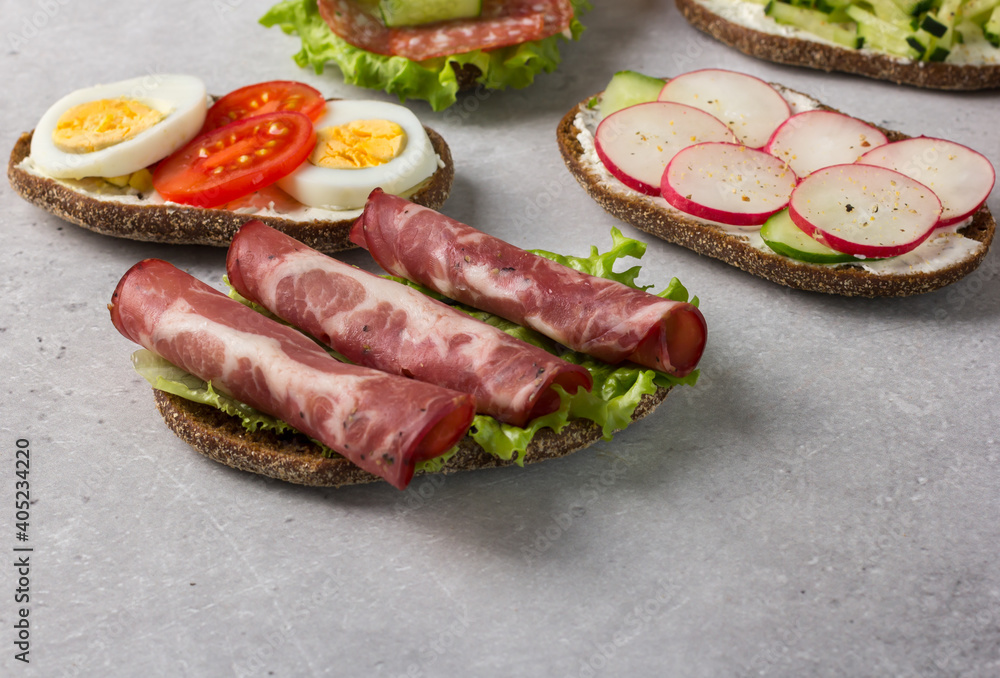 Open sandwiches on rye bread with cream cheese, ham, egg, radish, tomato. Open sandwiches on rye bread with cream cheese, ham, egg, radish, tomato.