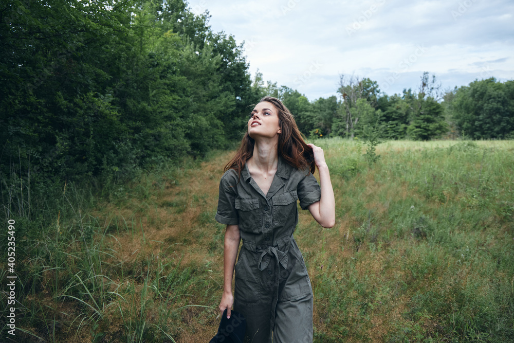 Woman in the field Looking up green jumpsuit holding her hair 