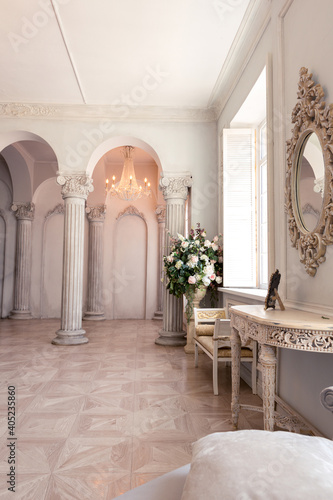 Luxurious light interior of the living room in the baroque style as in a royal castle with old stylish vintage furniture, columns, stucco on the walls