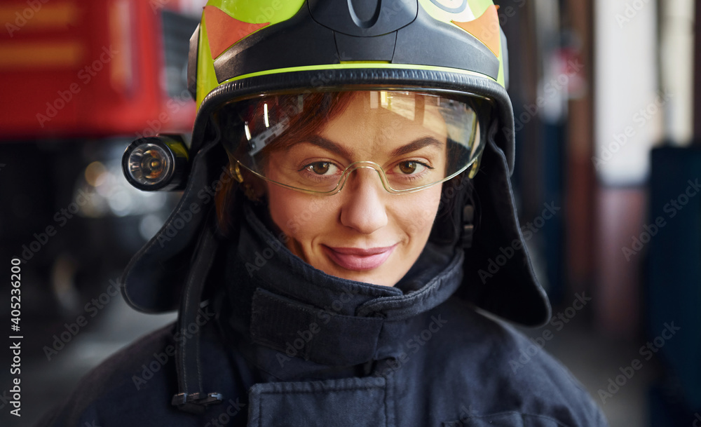 Close up view. Female firefighter in protective uniform standing near truck Close up view. Female firefighter in protective uniform standing near truck