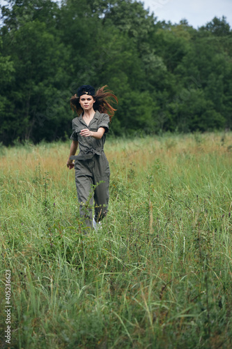 Woman in the meadow running on tall grass in green jumpsuit  © SHOTPRIME STUDIO