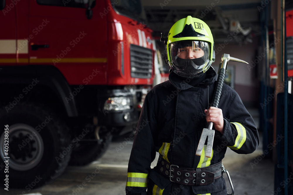Naklejka premium Male firefighter in protective uniform standing near truck