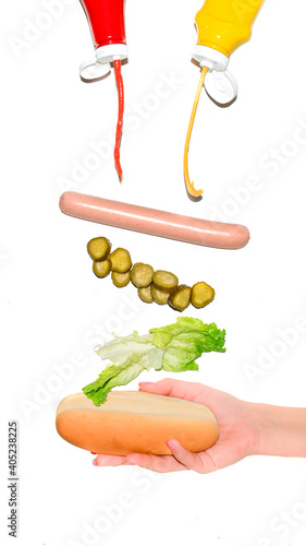 Holding a Hot dog with different ingredients flying, isolated