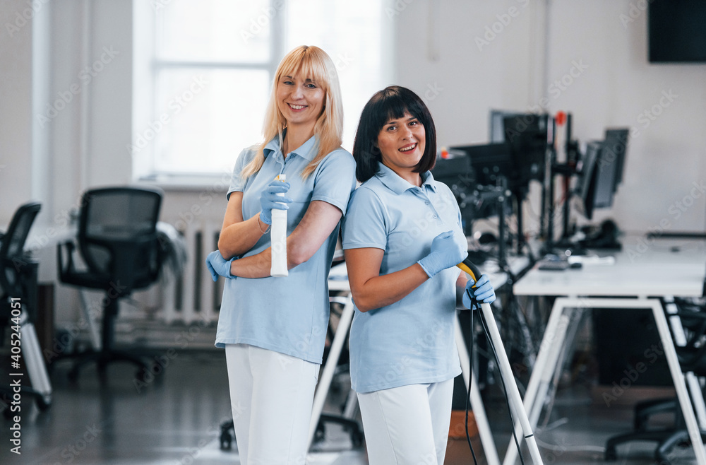 Fototapeta premium Group of workers clean modern office together at daytime