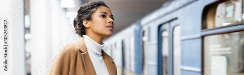 Foto curly african american woman looking at wagon of metro on blurred background, ba
