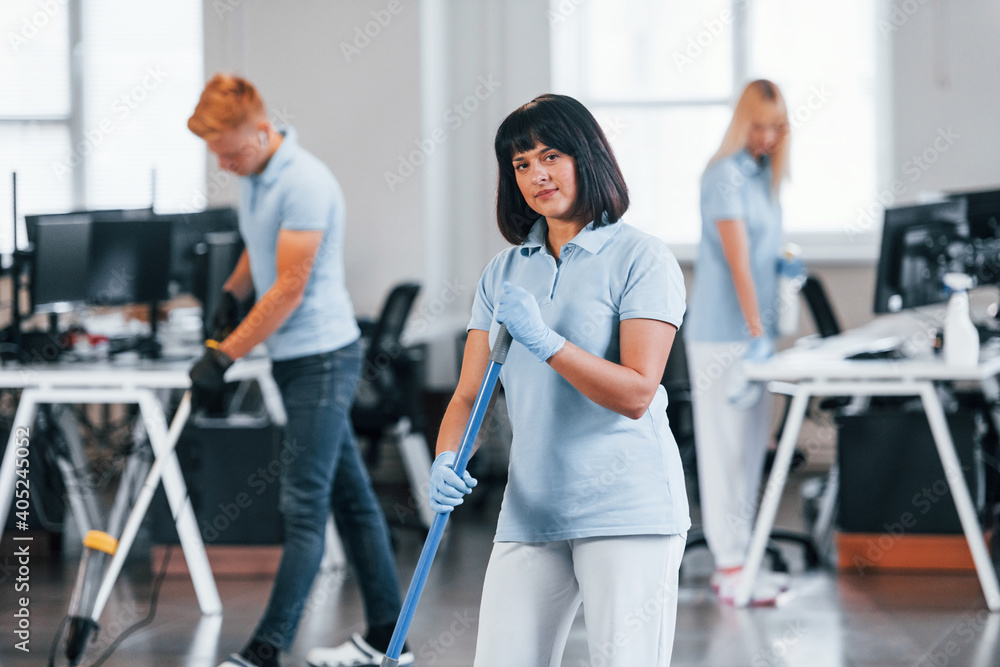 Fototapeta premium Group of workers clean modern office together at daytime