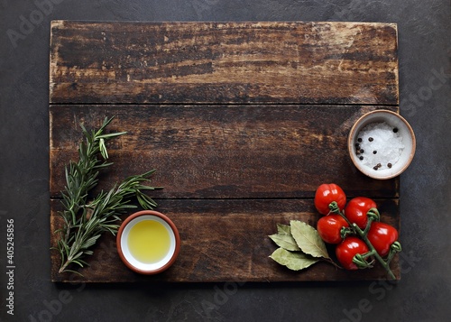 Selection of spices, herbs and vegetables on dark wooden cutting board. Ingredients for mediterranean cooking. Food background. Top view with copy space.