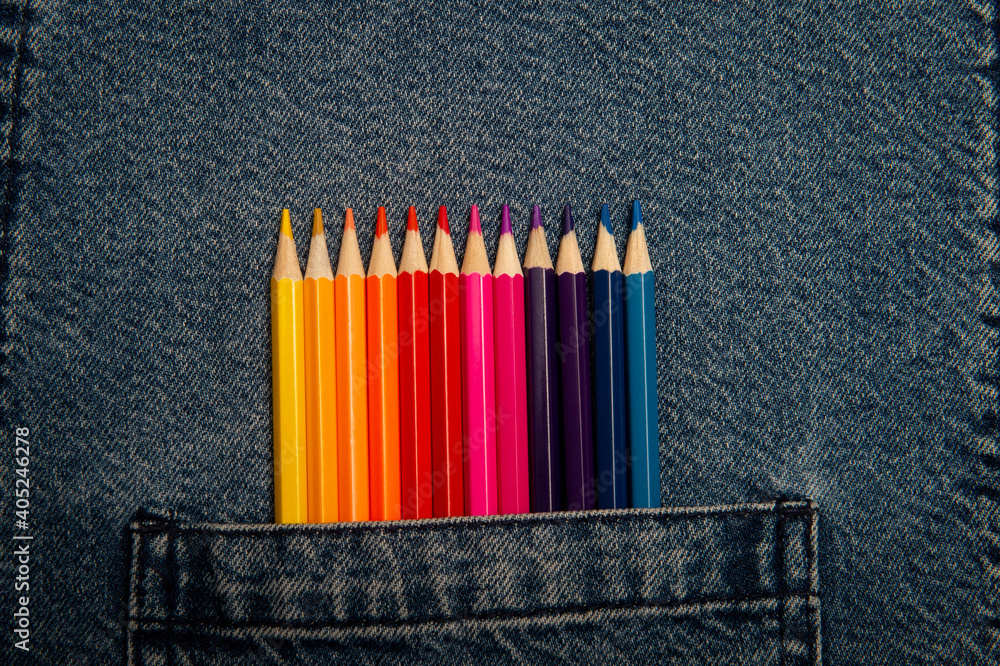 Colored pencils are in the pocket of denim pants. Jeans texture. Bright colored pencils. Colored pencils are in the pocket of denim pants. Jeans texture. Bright colored pencils.