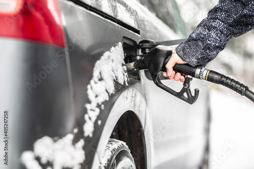 Canvas Print Fuel tank refilling during winter time with remains of snow on the car