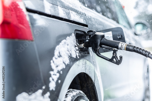 Fuel pistol left inside the car during petrol or gasoline refull at the station in freezing winter time photo