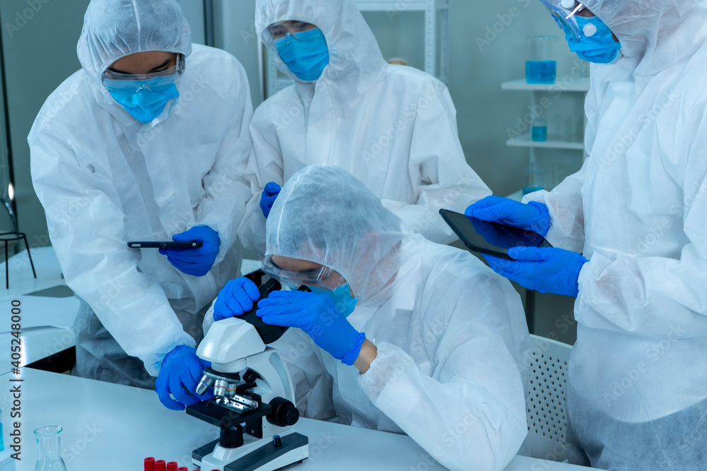Group of four Asian medical scientists wearing PPE protective suits working with blood sample in laboratory. Healthcare and medicine concept. virus pandemic concept. Group of four Asian medical scientists wearing PPE protective suits working with blood sample in laboratory. Healthcare and medicine concept. virus pandemic concept.