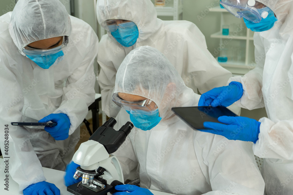 Group of four Asian medical scientists wearing PPE protective suits working with blood sample in laboratory. Healthcare and medicine concept. virus pandemic concept. Group of four Asian medical scientists wearing PPE protective suits working with blood sample in laboratory. Healthcare and medicine concept. virus pandemic concept.